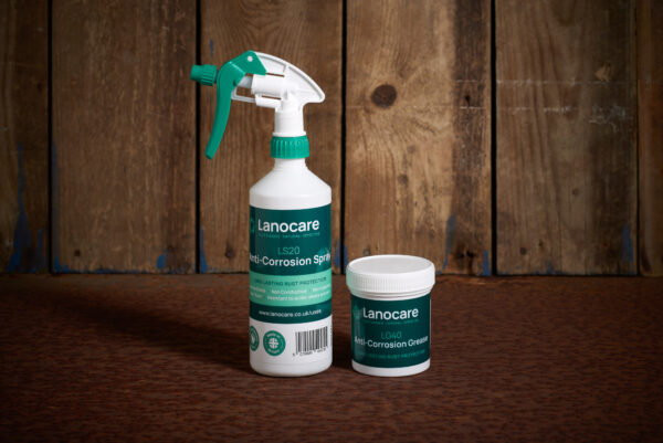 Lanocare anti-corrosion spray bottle with tub of anti-corrosion grease and wooden background